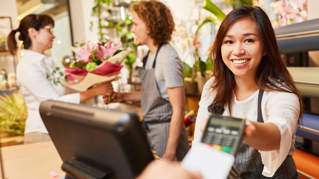 Una commessa riceve un pagamento con carta di credito contactless alla cassa di un negozio.