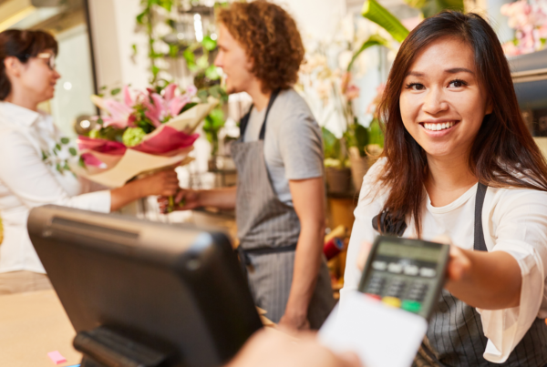 Una commessa riceve un pagamento con carta di credito contactless alla cassa di un negozio.
